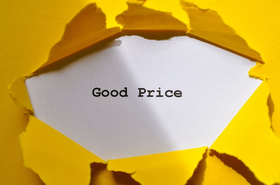 A close-up view of a yellow paper surface with a large, irregular tear revealing a white inner layer. Inside the torn area, a white card with black text reads 'Good Price.' The edges of the torn paper